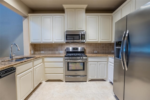 kitchen with backsplash, light stone countertops, sink, and appliances with stainless steel finishes