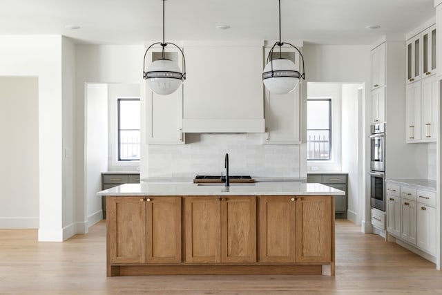 kitchen with an island with sink, brown cabinets, glass insert cabinets, and white cabinets