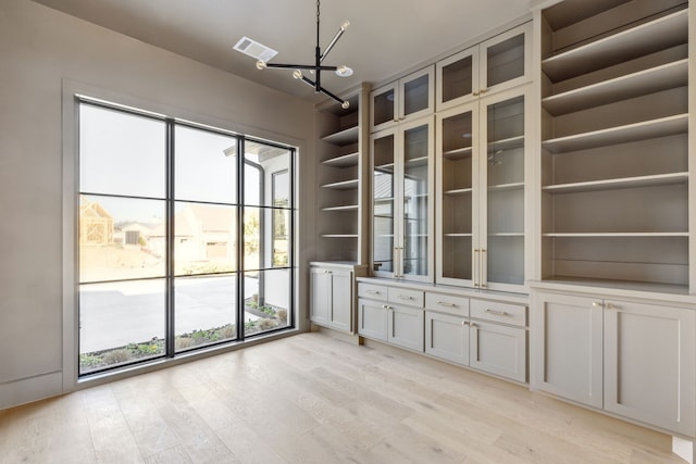 unfurnished room with light wood-style floors, a chandelier, and visible vents