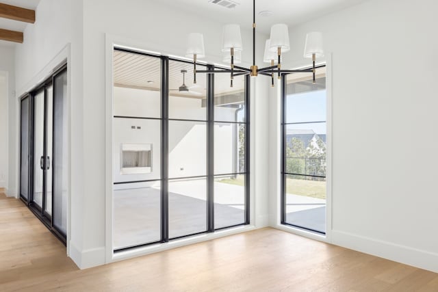 interior space featuring light wood-type flooring, visible vents, a notable chandelier, and baseboards