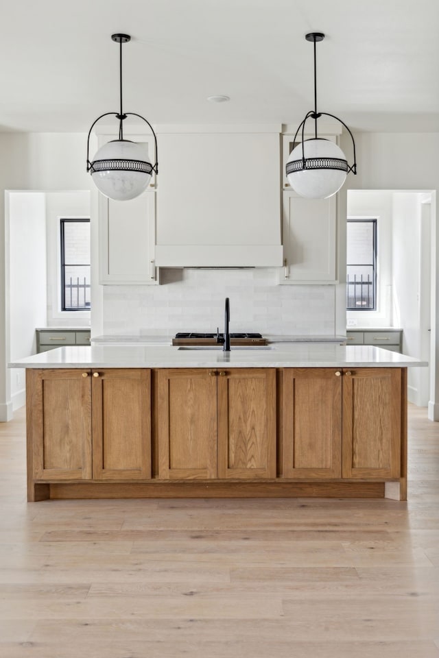 kitchen featuring light countertops, a sink, white cabinetry, and pendant lighting