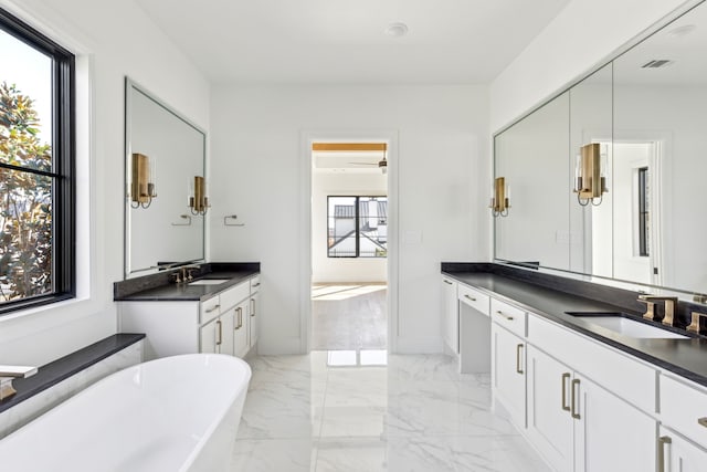 bathroom with marble finish floor, two vanities, a sink, and a healthy amount of sunlight