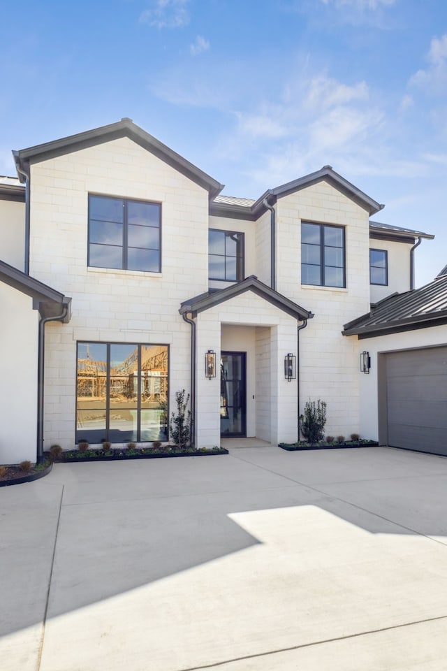 view of front facade with a garage, driveway, a standing seam roof, and metal roof