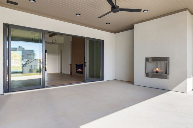 view of patio / terrace featuring a ceiling fan and a warm lit fireplace