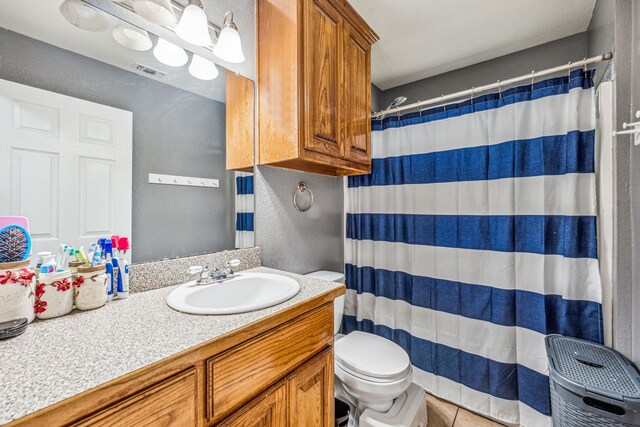 bathroom with toilet, vanity, tile patterned floors, and walk in shower