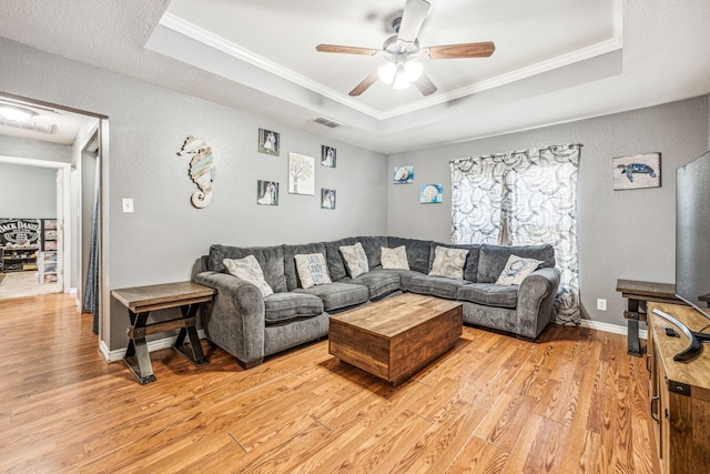 living room featuring a tray ceiling, crown molding, and hardwood / wood-style floors