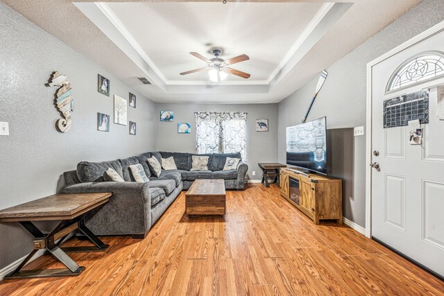 living room featuring light hardwood / wood-style flooring, a raised ceiling, and ceiling fan