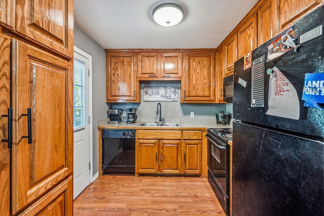 kitchen with a textured ceiling, sink, light hardwood / wood-style flooring, and black appliances