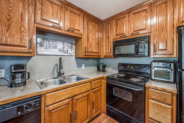 kitchen with sink, black appliances, a textured ceiling, and light hardwood / wood-style floors