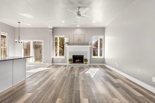 unfurnished living room with wood finished floors, a healthy amount of sunlight, visible vents, and a premium fireplace