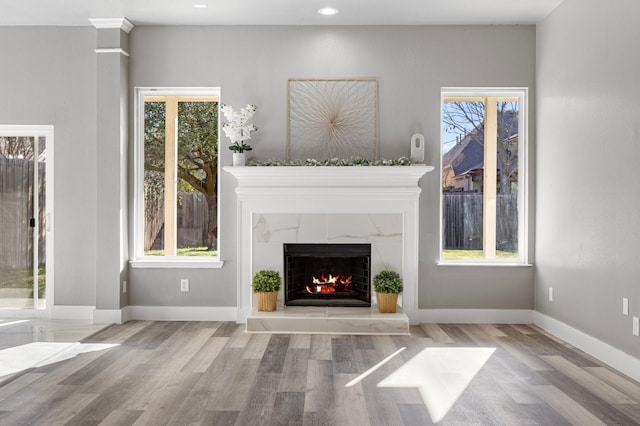 unfurnished living room featuring a wealth of natural light, a fireplace, and wood finished floors