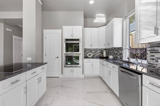 kitchen with dark stone counters, stainless steel appliances, white cabinets, marble finish floor, and tasteful backsplash