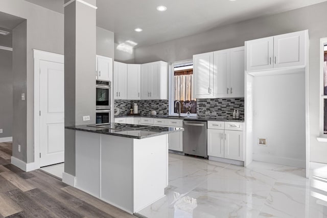 kitchen with baseboards, backsplash, appliances with stainless steel finishes, and white cabinetry