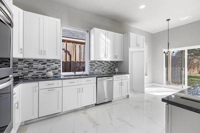 kitchen featuring a sink, stainless steel appliances, backsplash, and white cabinets