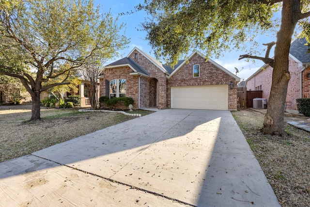 traditional-style home featuring brick siding, an attached garage, fence, central AC unit, and driveway