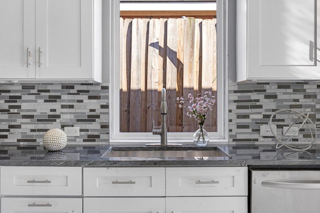 kitchen featuring dishwasher, tasteful backsplash, white cabinetry, and a sink