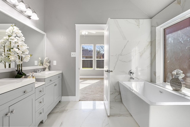 bathroom featuring marble finish floor, a freestanding bath, vanity, and baseboards