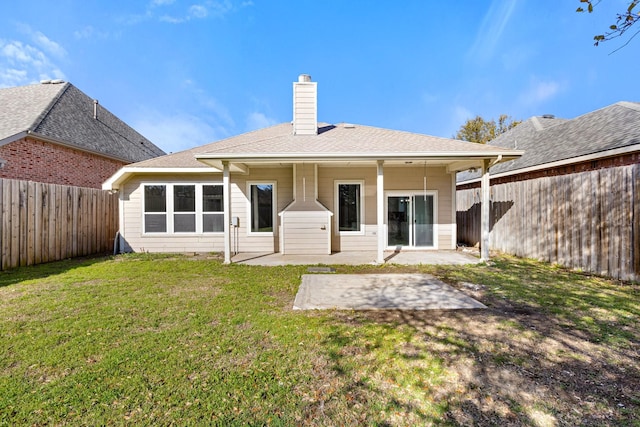 rear view of house with a patio area, a lawn, a chimney, and a fenced backyard