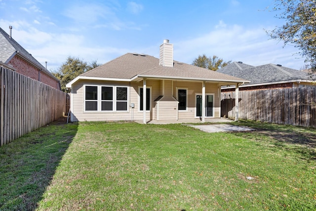 back of house featuring a lawn, a patio, a fenced backyard, a shingled roof, and a chimney