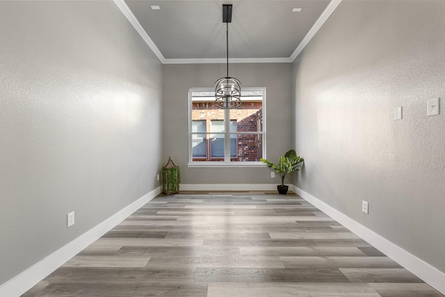 unfurnished dining area with an inviting chandelier, crown molding, wood finished floors, and baseboards