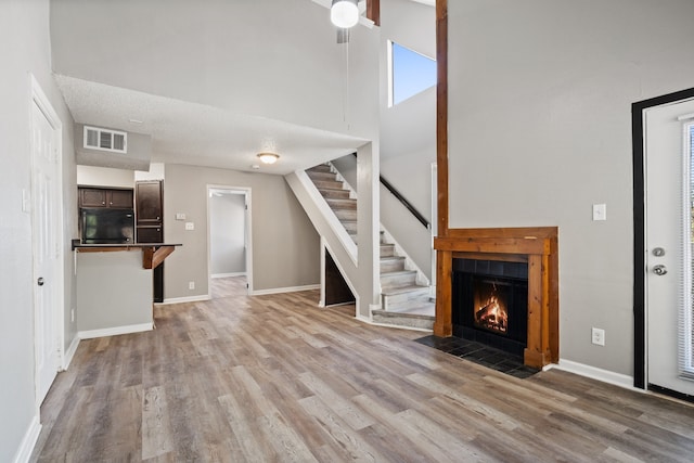 unfurnished living room with a high ceiling, a textured ceiling, and light hardwood / wood-style floors