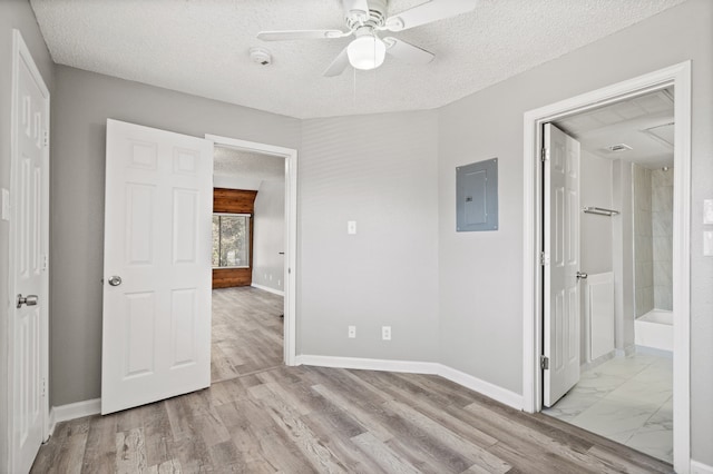 unfurnished bedroom with connected bathroom, ceiling fan, light hardwood / wood-style flooring, electric panel, and a textured ceiling