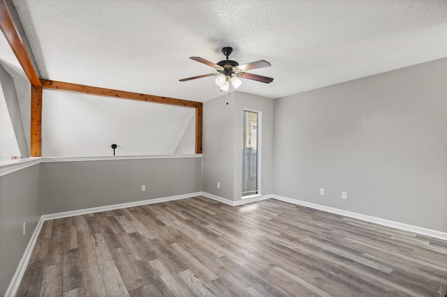 spare room featuring vaulted ceiling with beams, ceiling fan, hardwood / wood-style floors, and a textured ceiling