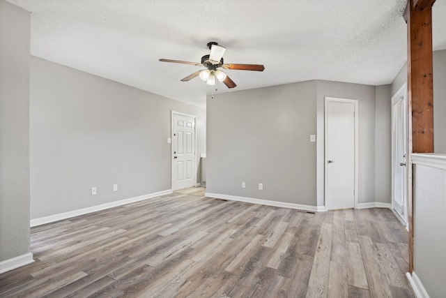 spare room with a textured ceiling, light wood-type flooring, and ceiling fan