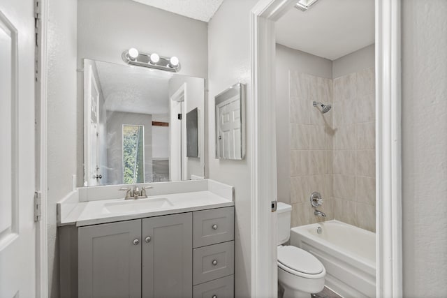 full bathroom featuring tiled shower / bath combo, toilet, a textured ceiling, and vanity