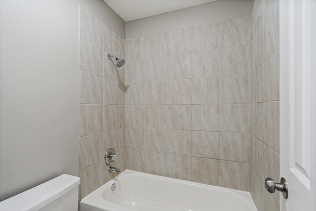 bathroom with tiled shower / bath combo and toilet