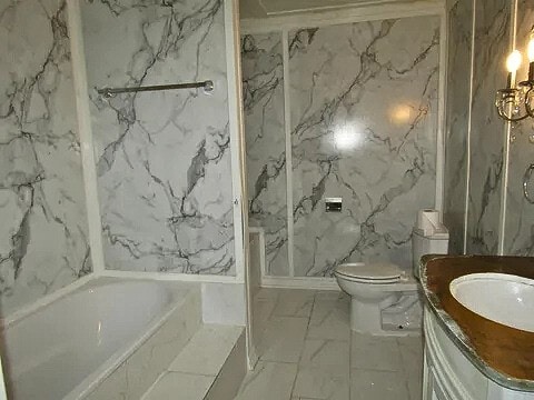 bathroom with vanity, a bathtub, toilet, and tile walls