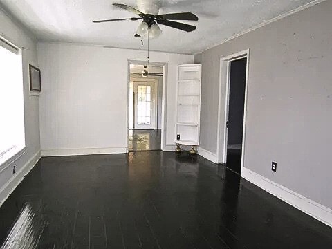 empty room with ceiling fan and dark wood-type flooring