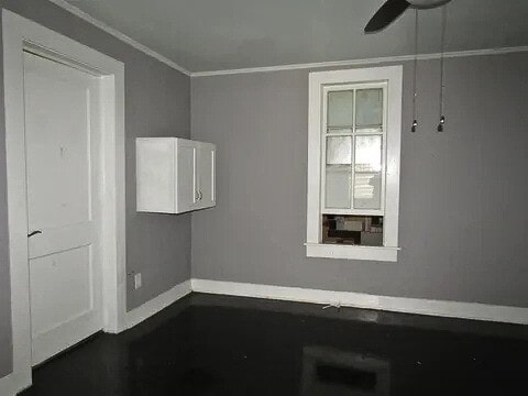 empty room featuring ceiling fan and crown molding