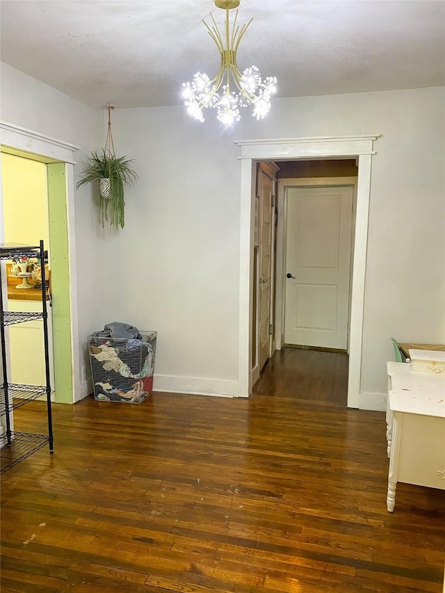 corridor with dark hardwood / wood-style floors and an inviting chandelier