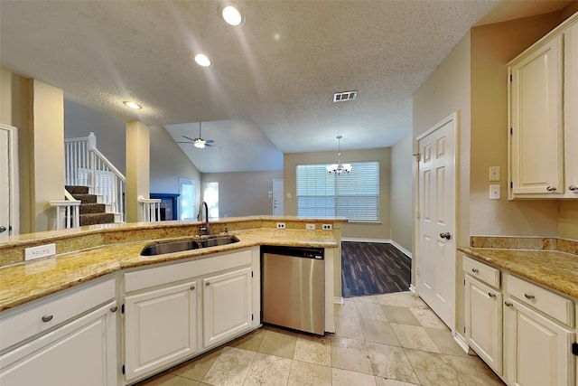 kitchen featuring dishwasher, a textured ceiling, vaulted ceiling, and sink