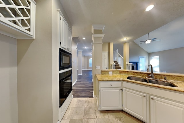 kitchen with lofted ceiling, black appliances, sink, light wood-type flooring, and white cabinetry