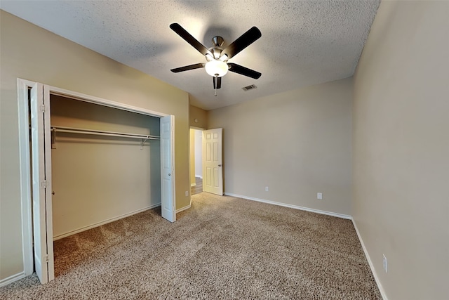 unfurnished bedroom with carpet, ceiling fan, a textured ceiling, and a closet