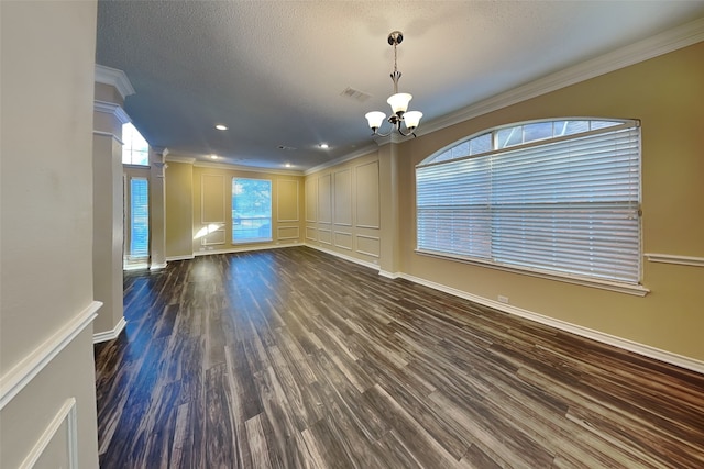 unfurnished living room with dark hardwood / wood-style floors, ornamental molding, a textured ceiling, a notable chandelier, and decorative columns