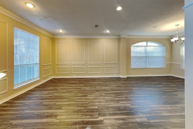 empty room with ornamental molding, wood finished floors, a textured ceiling, a chandelier, and a decorative wall