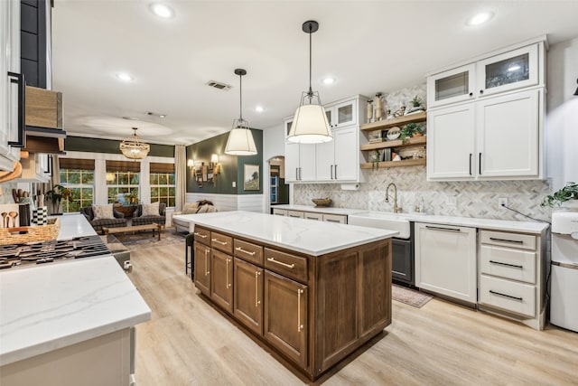 kitchen featuring pendant lighting, white cabinetry, a kitchen island, and light hardwood / wood-style floors