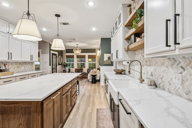 kitchen featuring light stone countertops, pendant lighting, light hardwood / wood-style flooring, and white cabinetry