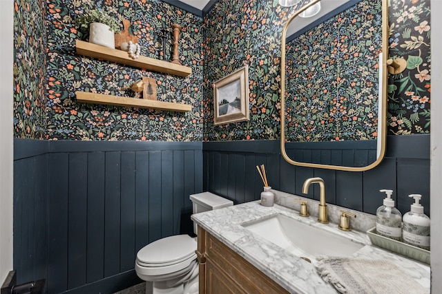 bathroom with vanity, wood walls, and toilet