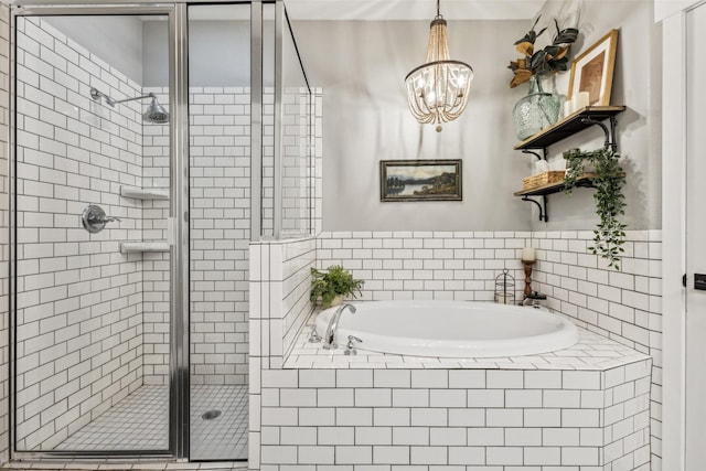full bathroom featuring a stall shower, a bath, and a chandelier