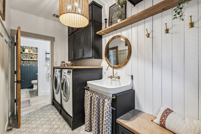 laundry room with light floors, cabinet space, separate washer and dryer, and visible vents