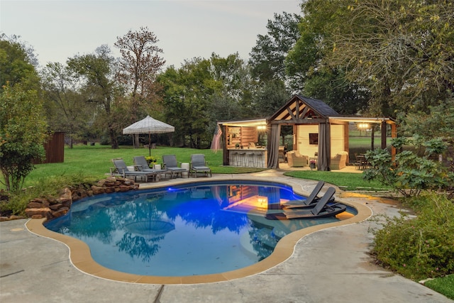 view of pool featuring an outbuilding, a yard, exterior bar, and a patio