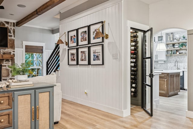 bar featuring decorative backsplash, light hardwood / wood-style flooring, beamed ceiling, and ornamental molding