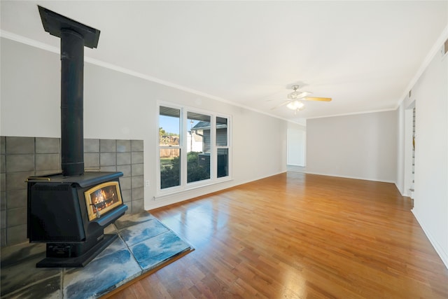 living room with ceiling fan, crown molding, wood-type flooring, tile walls, and a wood stove