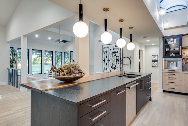 kitchen with pendant lighting, light wood-type flooring, sink, and a kitchen island with sink