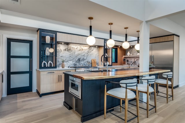 kitchen with wooden counters, pendant lighting, light hardwood / wood-style flooring, and sink