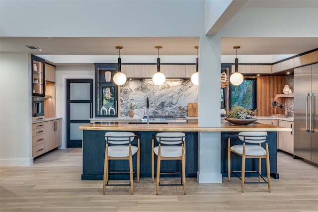 kitchen featuring a kitchen breakfast bar, light hardwood / wood-style flooring, pendant lighting, and appliances with stainless steel finishes